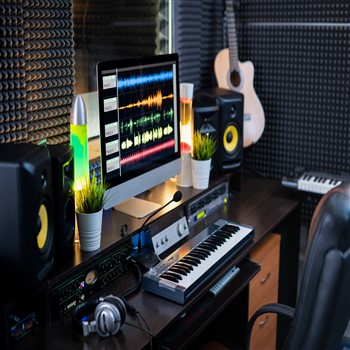 A musician-centric recording studio equipped with a computer, keyboard, and guitar, promoting growth and skill enhancement.