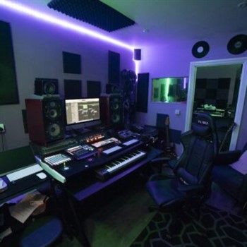 A recording studio available for hire equipped with a desk and monitors.