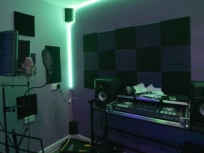 A recording studio specialising in artist development, equipped with green lighting and state-of-the-art equipment.