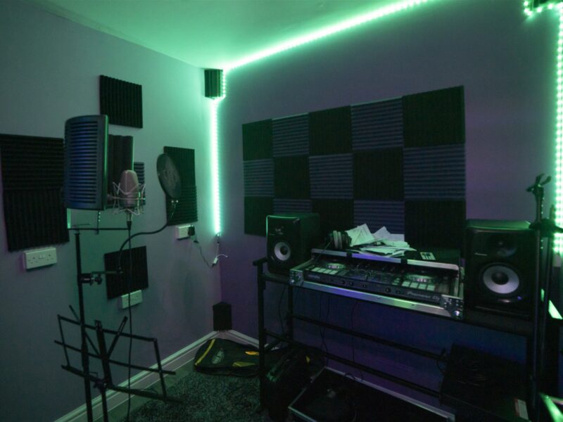 A recording studio with green lighting and equipment.