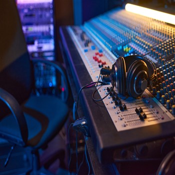 Headphones in a recording studio on top of an audio mixing board.