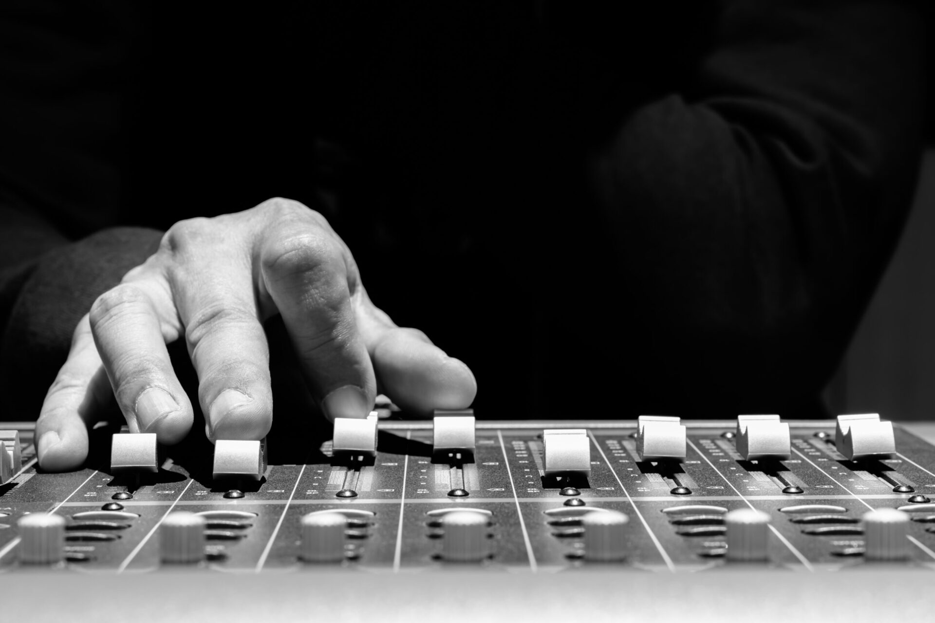 A monochrome portrait of an individual operating a mixing board, illustrating possible pricing and package options.