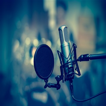 A microphone in front of a recording studio, where you can discover music and merchandise at Orb Music Studio Shop.