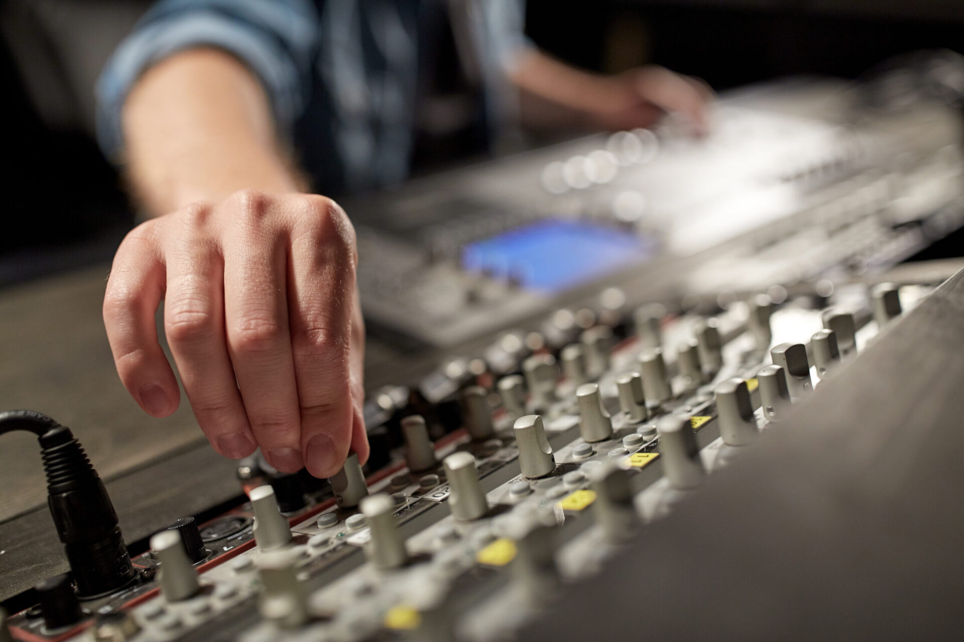 A person's hand is touching a mixing board while demo recording.